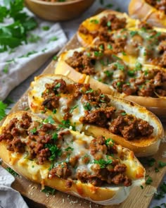 three stuffed spaghetti boats on a wooden cutting board with parsley around the edges and two bowls of pasta in the background