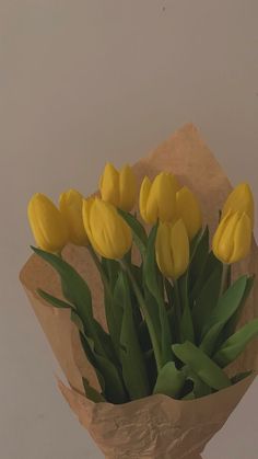 a bouquet of yellow tulips sitting on top of a piece of brown paper