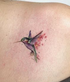 a small hummingbird tattoo on the back of a woman's shoulder