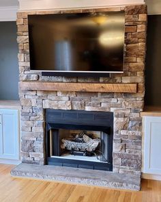 a flat screen tv mounted above a stone fireplace