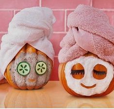 two pumpkins with faces painted to look like they are wearing towels on their heads