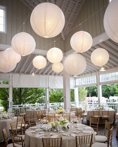 a room filled with lots of tables covered in white paper lanterns