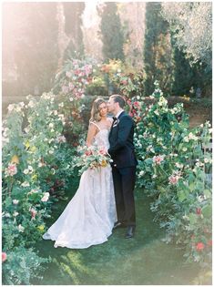 a bride and groom are standing in front of flowers at the end of their wedding day