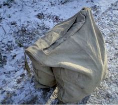 an old bag sitting in the snow on top of a field covered with snow and grass