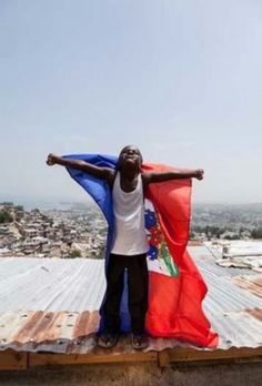 a man standing on top of a roof holding a red, white and blue flag