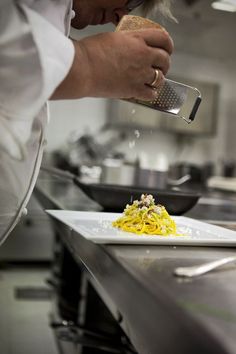 a chef is sprinkling cheese on top of some food in a kitchen area