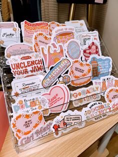 many different stickers are sitting on a wooden table with a chair in the background