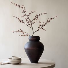 a vase with flowers in it sitting on a table next to a plate and bowl