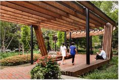 two people sitting on a wooden bench under a pergolated roof in a park