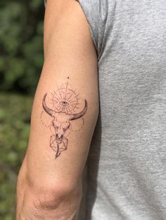 a man with a tattoo on his arm has a bull's skull and compass