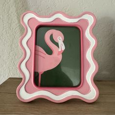 a pink and white flamingo frame sitting on top of a wooden table