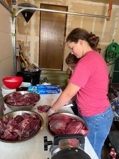 a woman in pink shirt preparing food on top of a counter next to pans