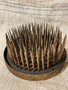 a close up of a hair brush on a cloth surface with some rusted metal pins sticking out of it