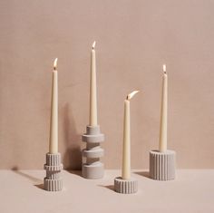 three candles are lined up next to each other on top of cement blocks, with one candle in the middle surrounded by smaller ones