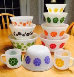 a table topped with lots of colorful bowls and cups on top of a wooden table