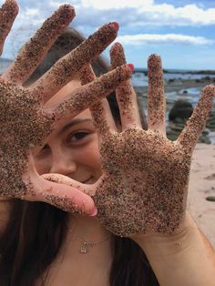 a young woman holding up her hands covered in sand