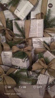 several wrapped books with bows and pine branches on them are stacked up in a pile