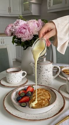 a person pouring syrup over pancakes on a plate