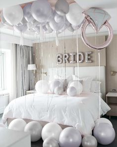 balloons are hanging from the ceiling above a bed