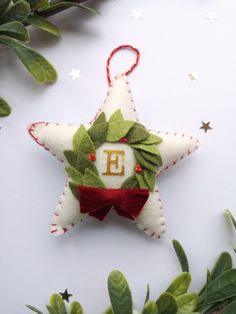 a christmas ornament hanging from the side of a tree with leaves and stars around it