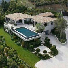 an aerial view of a large house with a pool in the middle and trees surrounding it