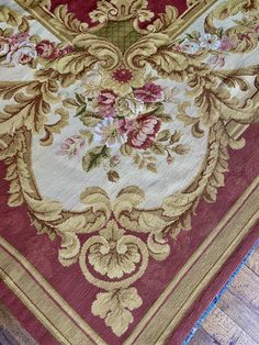 a large red and gold rug with flowers on the bottom is laying on top of a hard wood floor