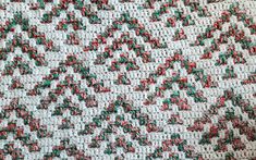 a close up view of a crocheted blanket with red, green and white colors