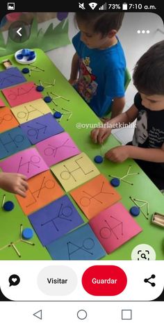 two children are playing with letters and numbers made from construction paper on a table in front of them