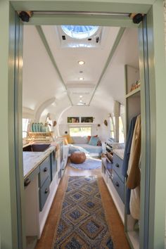 the inside of an airstream with blue cabinets and rugs on the floor is shown