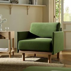 a green chair sitting on top of a hard wood floor next to a wooden table