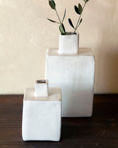 two white vases sitting on top of a wooden table