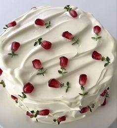 a cake with white frosting and red roses on it's top is sitting on a plate