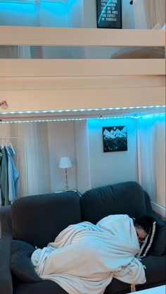 a person laying on top of a couch under a loft bed