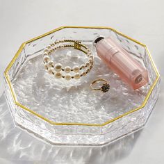 an assortment of jewelry sitting on a glass tray with gold trimmings and pearls