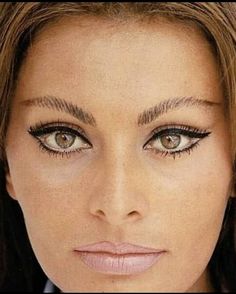 a close up of a woman's face with long hair and eyeliners