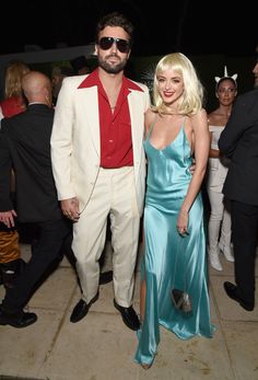 a man and woman in formal wear standing next to each other at an outdoor event