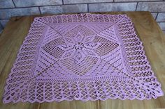 a pink doily sitting on top of a wooden table next to a brick wall