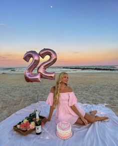 a woman sitting on top of a blanket next to a cake and number 25 balloon