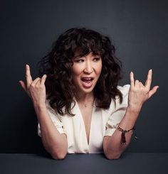 a woman sitting at a table with her hands in the air