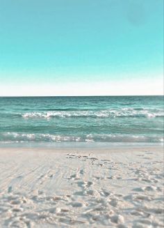 an empty beach with waves coming in and out of the water on a sunny day