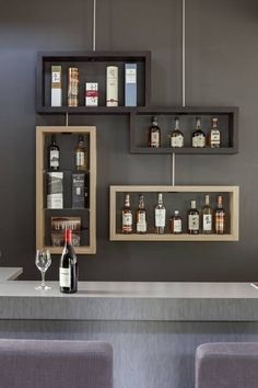 a bar with liquor bottles and wine glasses on the top shelf next to two empty shelves