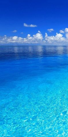 an ocean view with clear blue water and clouds