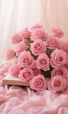 a bunch of pink roses sitting on top of a bed next to an open book