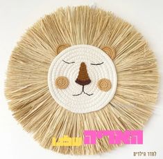 a lion face made out of straw with eyes closed and ears curled up, on a white wall