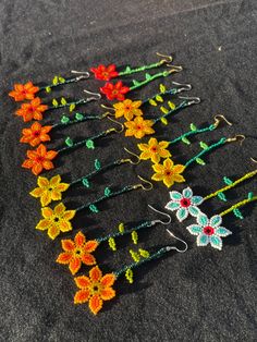 several pairs of colorful beaded hair pins on a black surface with white and red flowers