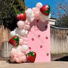 the balloon arch is decorated with strawberries and balloons