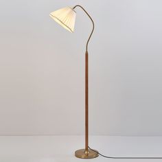 a floor lamp with a wooden base and a white shade on the top, standing upright