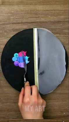 a person cutting paper with scissors on top of a wooden table next to a mirror