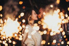 a man and woman standing next to each other in front of some bright lights at night