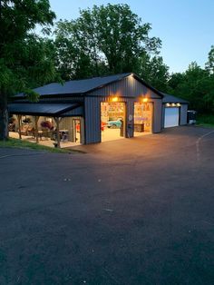 two garages with lights on in the middle of a parking lot next to trees